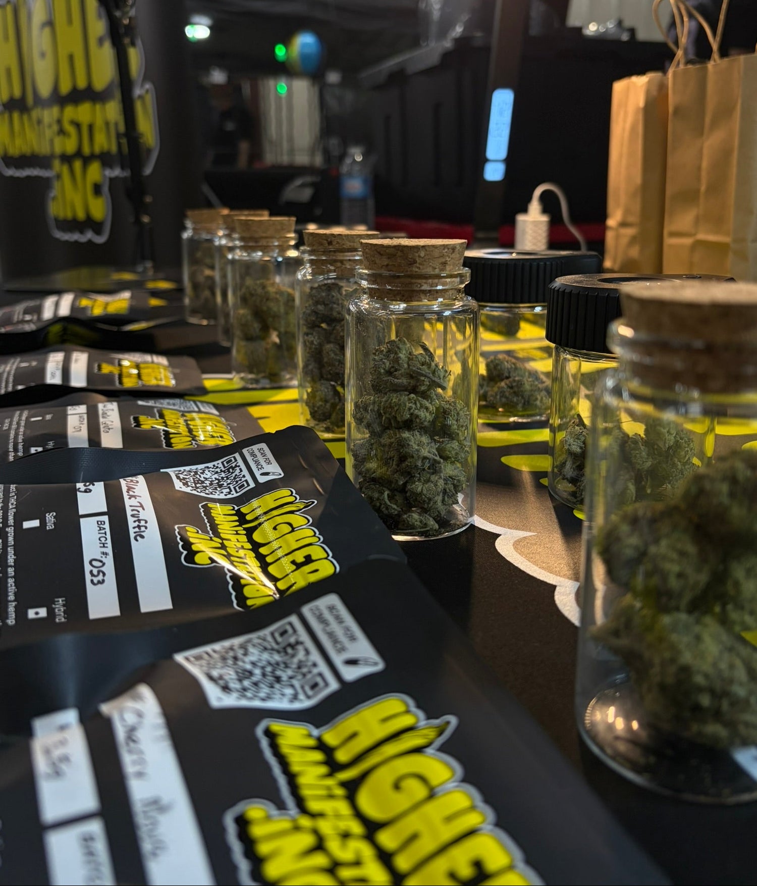 Jars of cannabis buds on branded packaging with a blurred indoor background